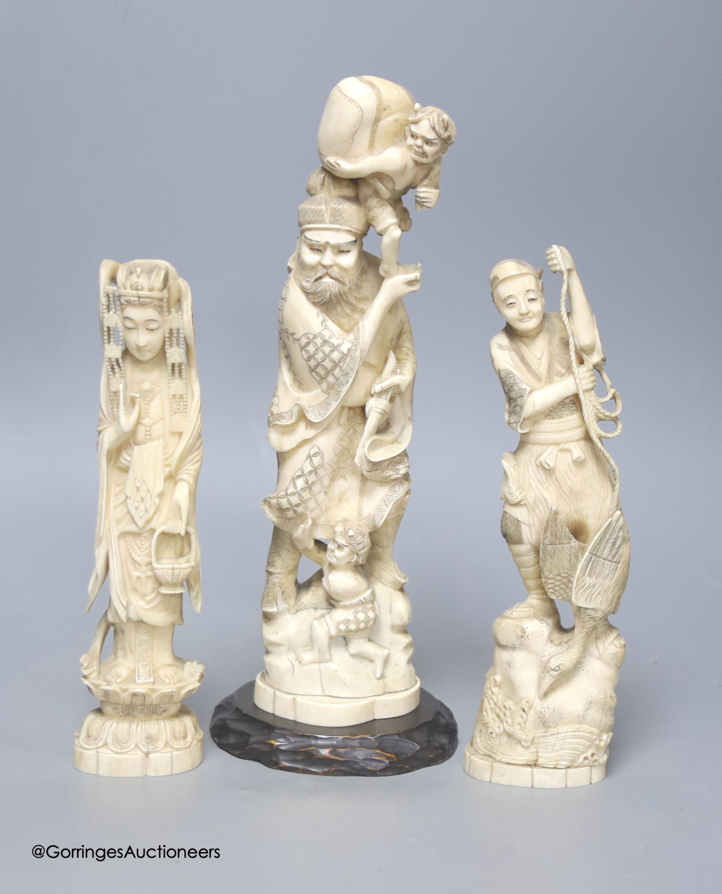Three Japanese carved walrus ivory okimono, early 20th century, tallest 32cm including wood stand